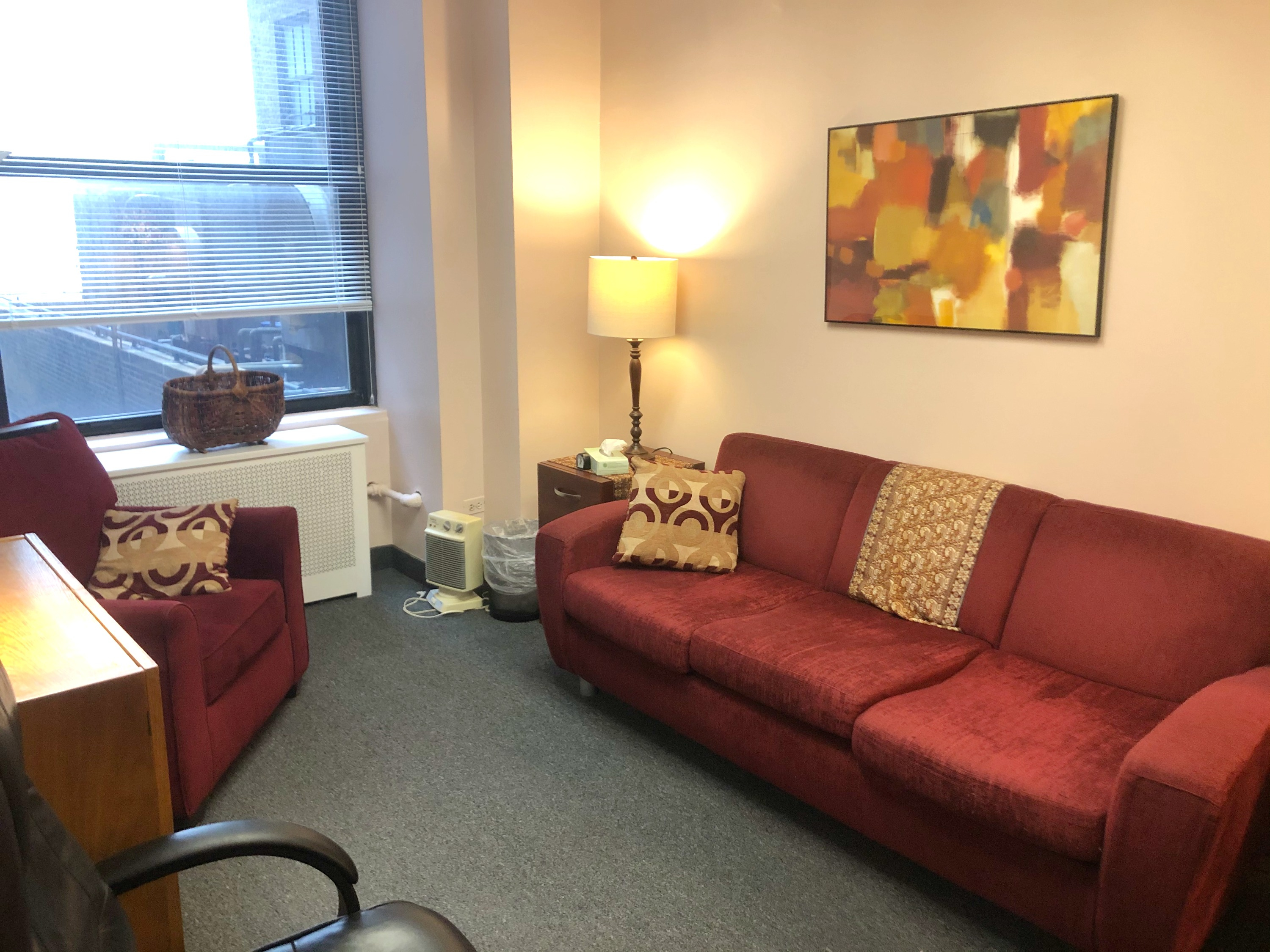 Cozy waiting area with couch, chairs, and lamp