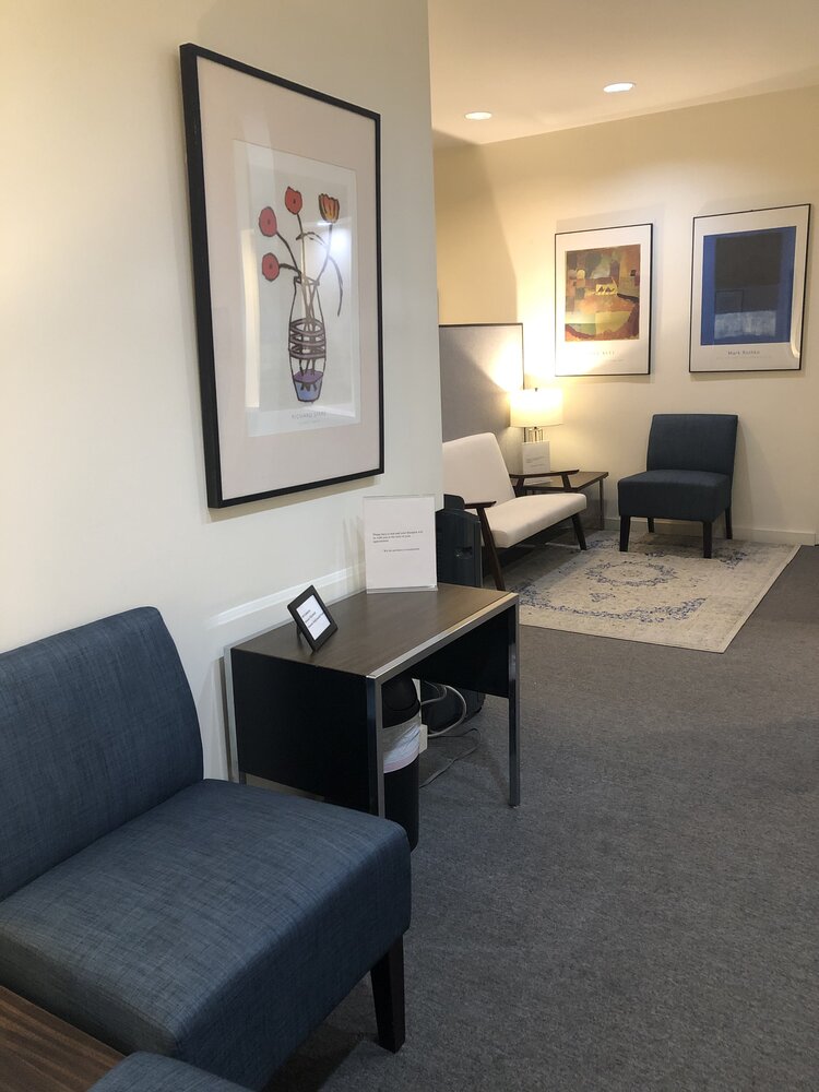 Cozy office corner with couch, rug, and paintings